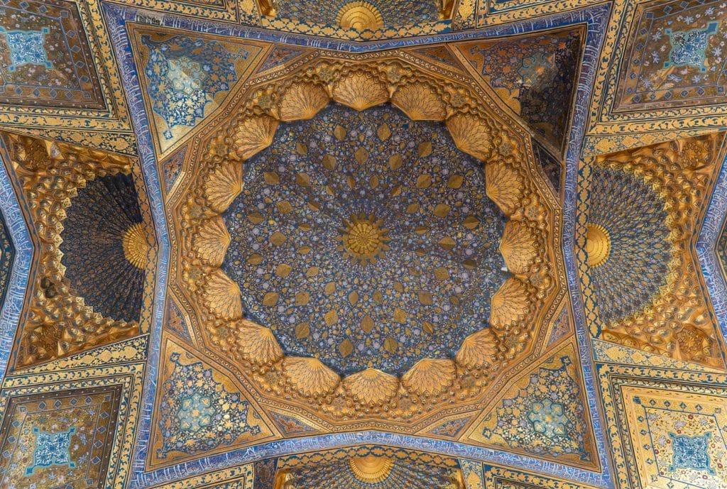 A close-up intricately patterned ceiling with bright blue and gold spirals and geometric patterns.