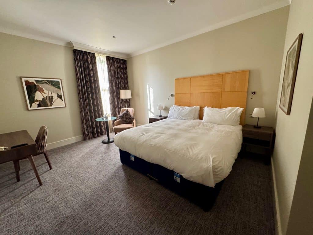 A hotel room with a big white bed.
