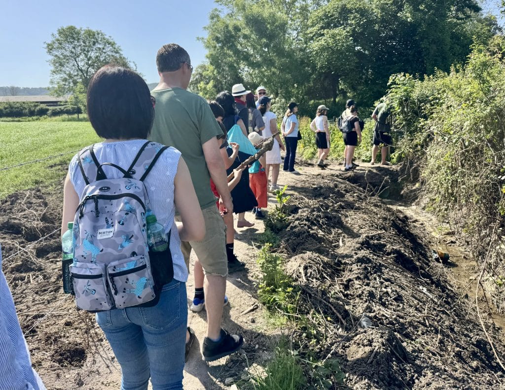 A group of people walking down a footpath in a line and waiting to go through a gate