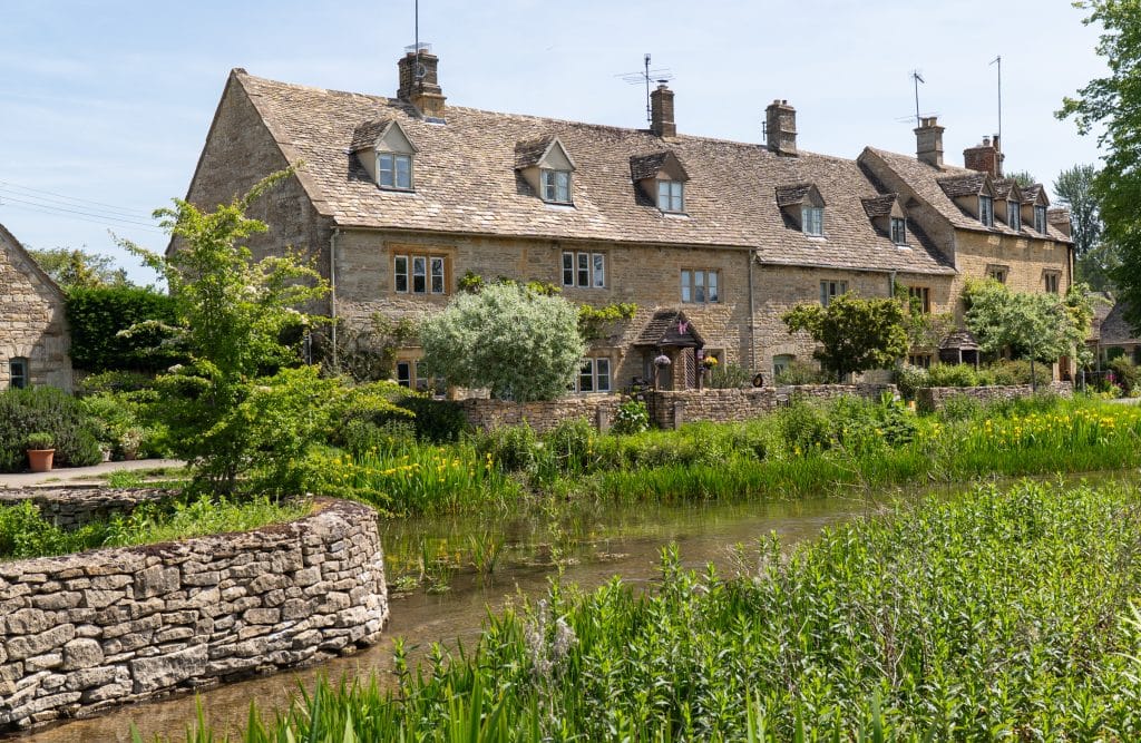 An old-fashioned golden stone house perched on a canal.