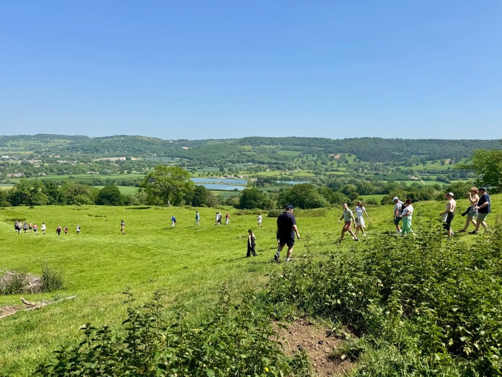 People waling down a hill with gorgeous undulating hills in the distance.