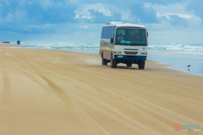 A truck that is driving down the beach