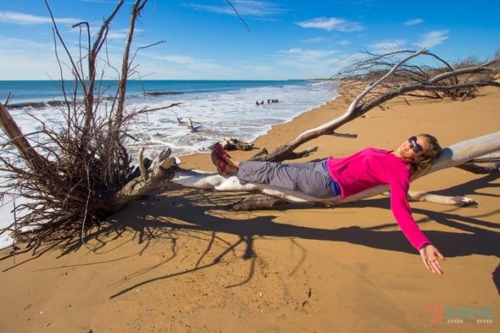 woman lying on driftwood on Rules Beach,