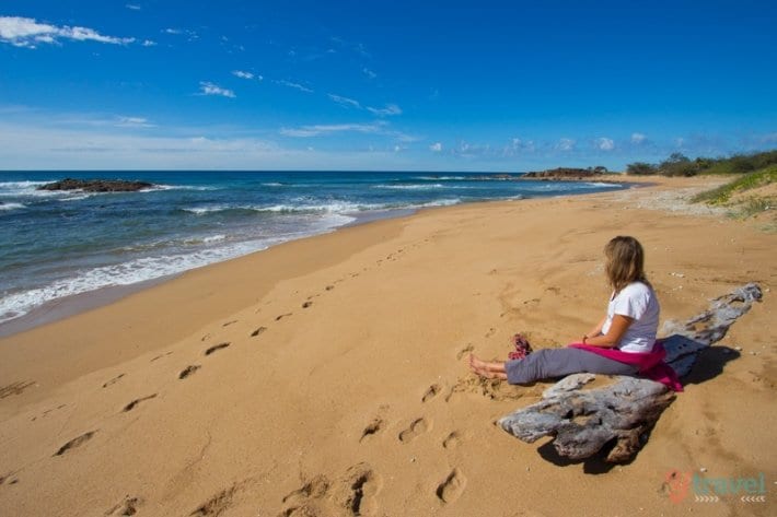 woman sitting on driftwood on Wreck Beach