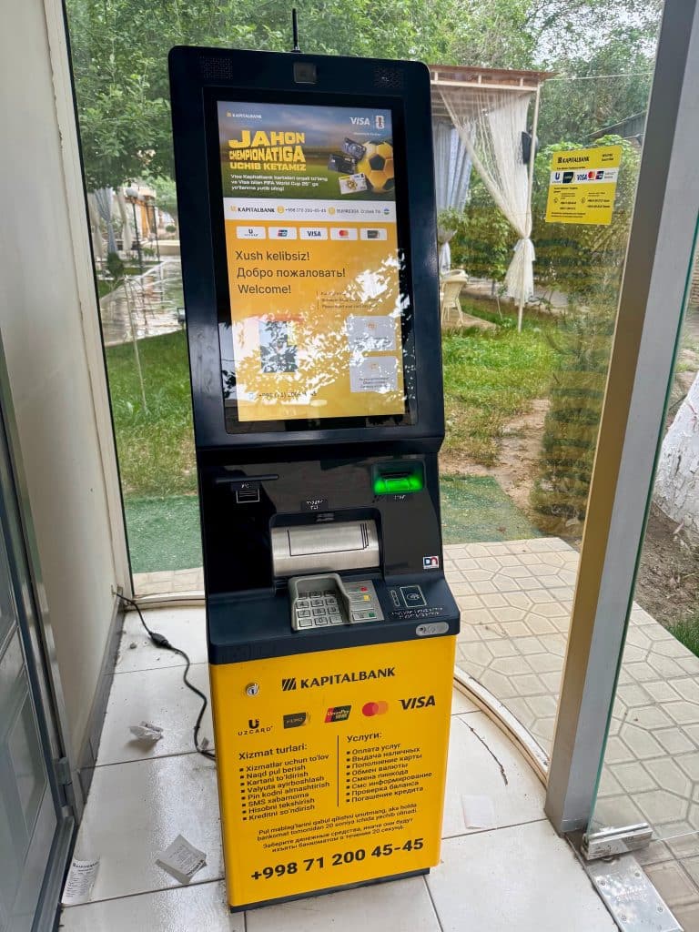 A yellow and black Kapitalbank ATM in a vestibule.