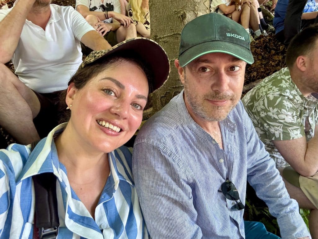 Kate and Charlie take a smiling selfie, looking sweaty and red as they just climbed the hill.