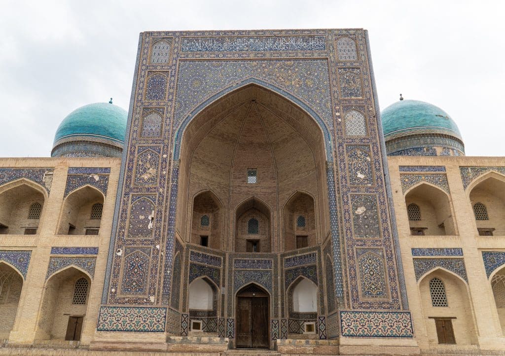 A big sand-colored madrasah covered with bright blue tile work in Bukhara.