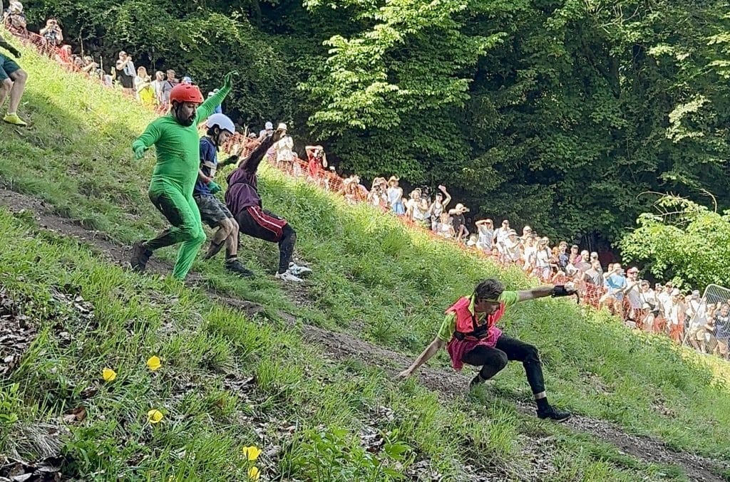 Three men running down the hill, one in a bright green onesie.