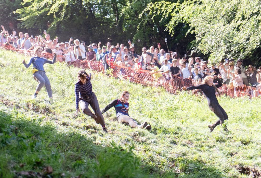Four women running and sliding down the hill