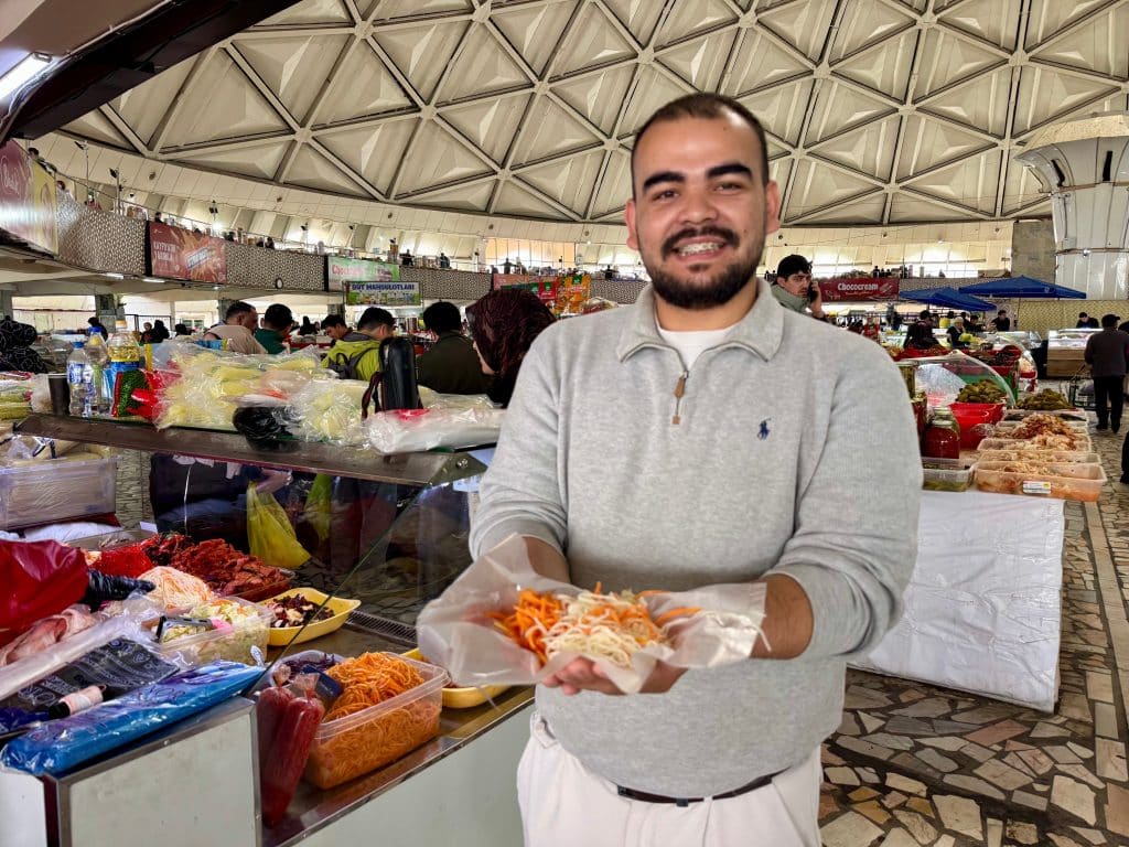 Guide Yusuf holds up a bag of pickled vegetables at Chorsu Bazaar.