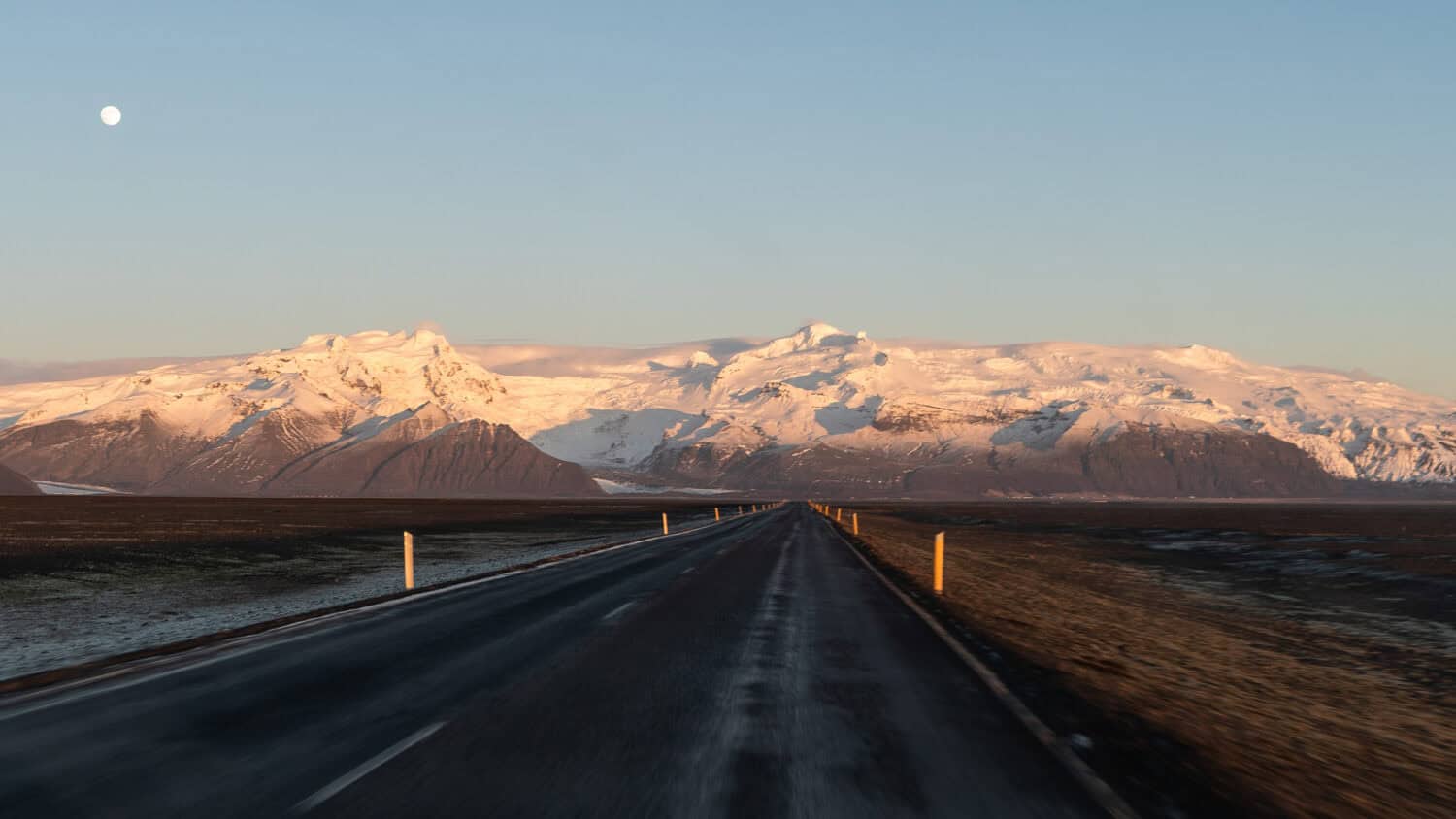 Driving towards Skaftafell Glacier at sunset with a full moon in Iceland.