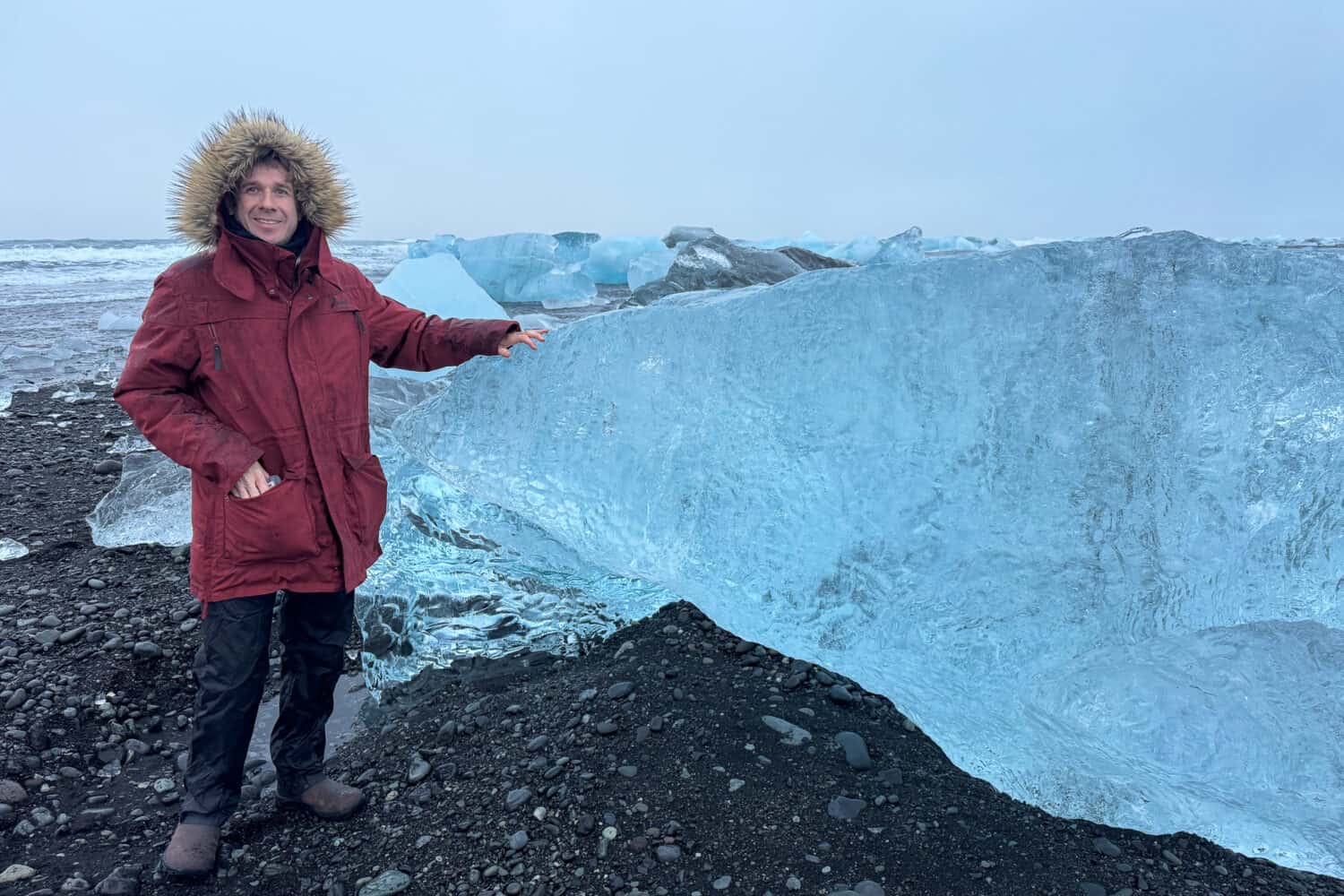 Simon next to a large iceberg at Diamond Beach in Iceland in winter.