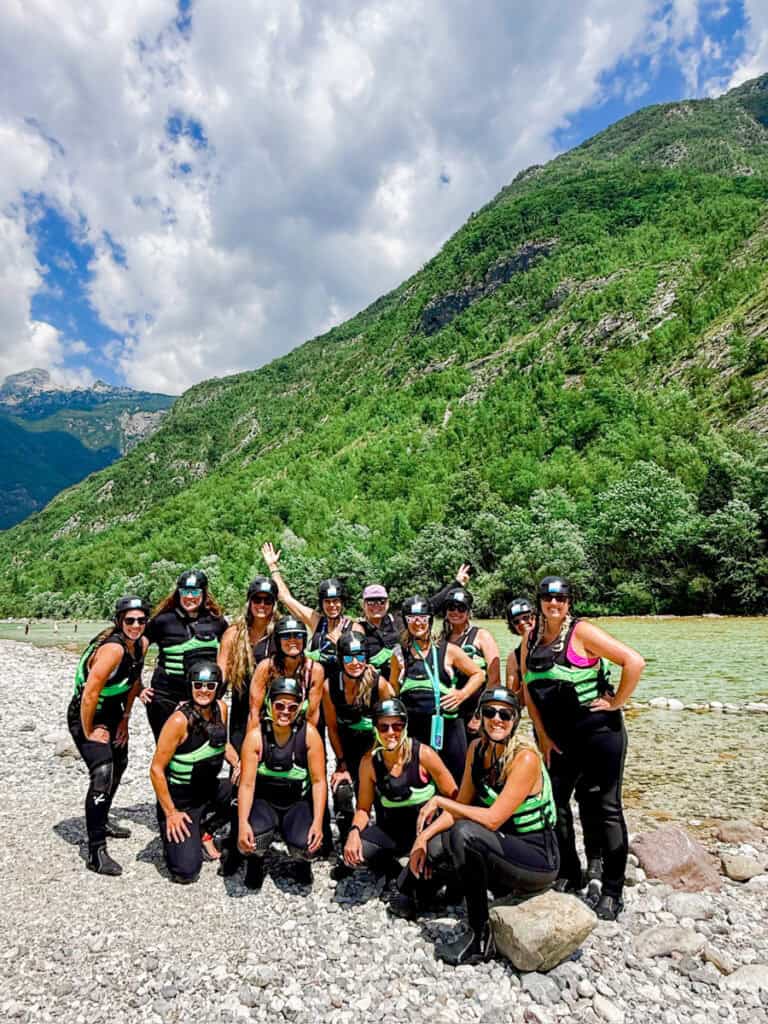 group of women on edge of river in wetsuits