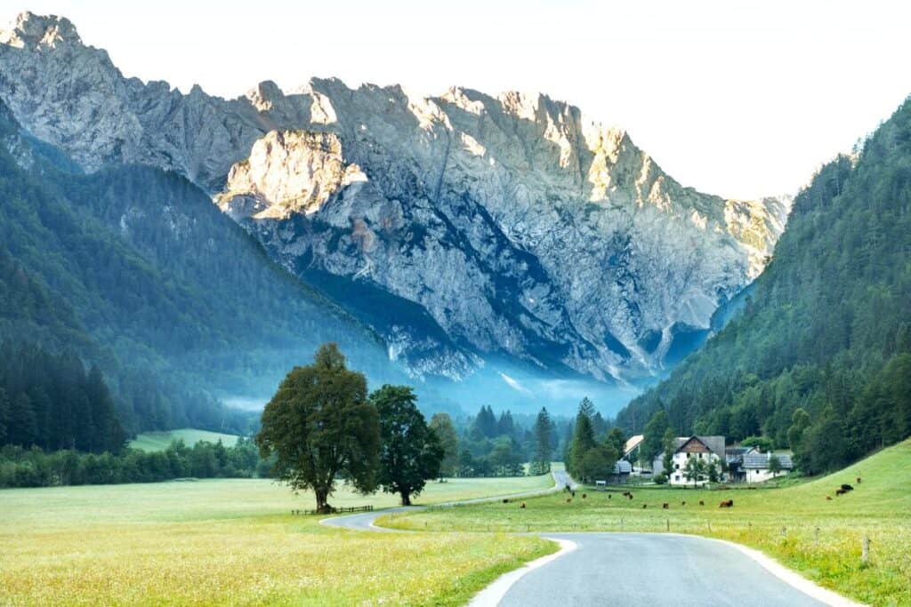 Logar valley, Slovenia in sunrise, mountain peaks brightly lit by golden colors of the sun.