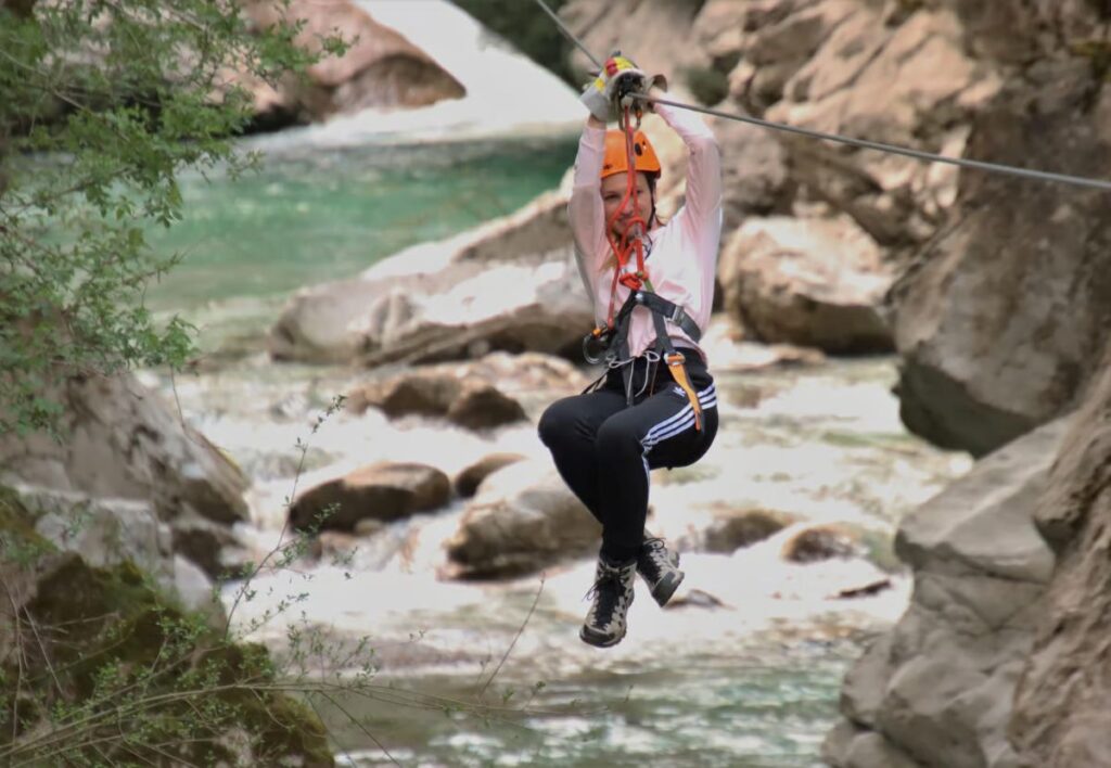 woman on zipline over river in Učja Canyon park 