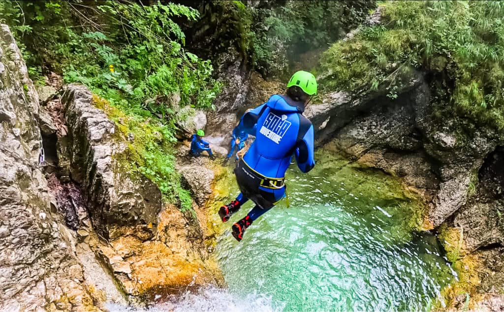 woman jumping from cliff into water