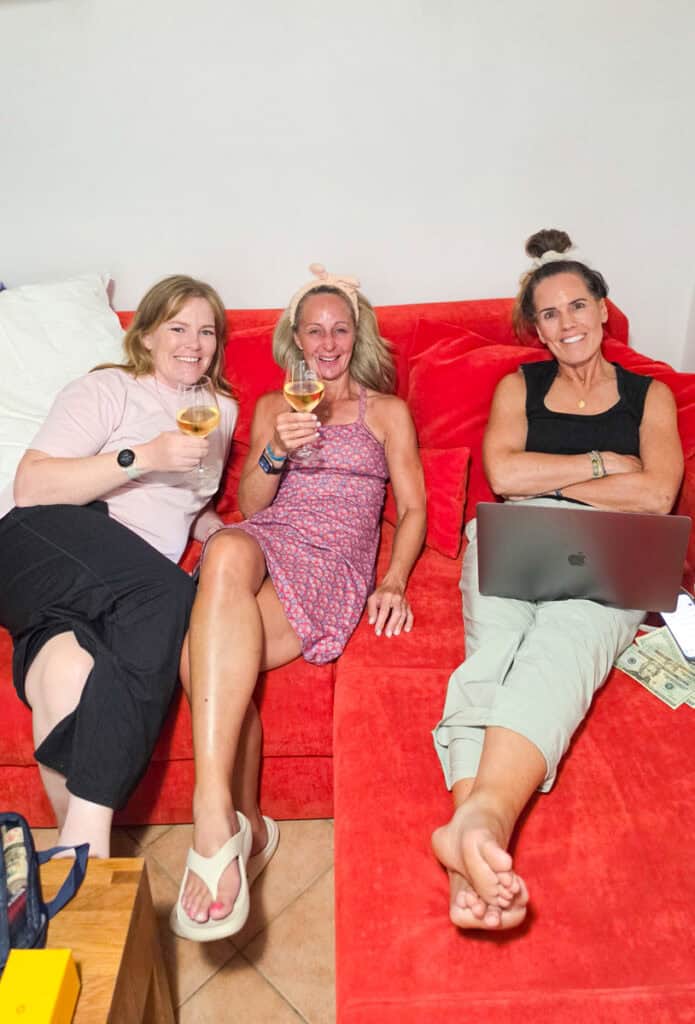 three women drinking wine in hotel room