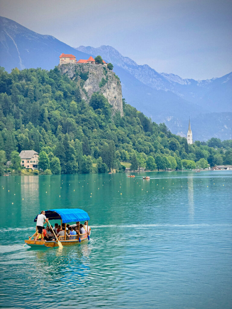 plenka boat going past bled castle on the hill