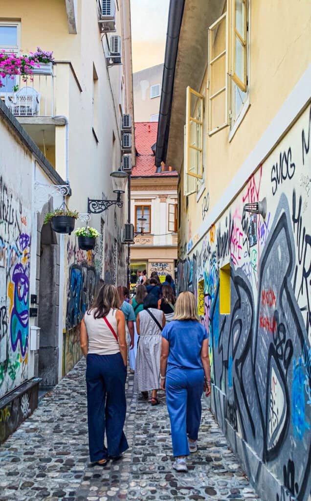 women walking down graffitti alley in ljubljana