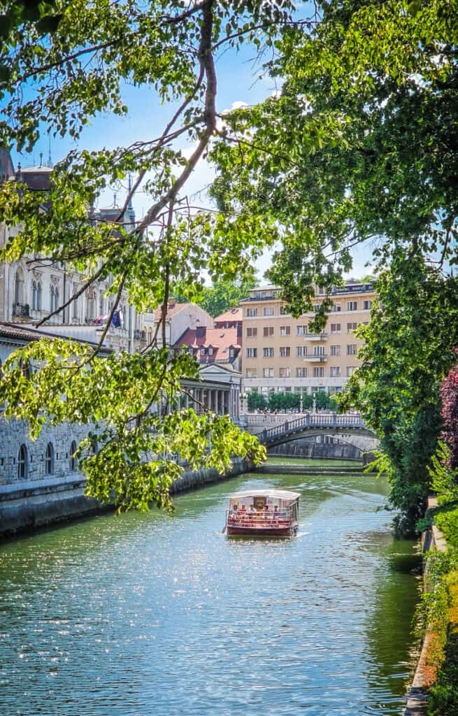 boat going down ljubljana river framed by trees