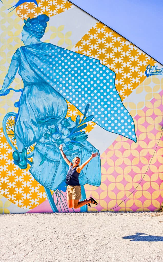 woman jumping next to mural ljubljana