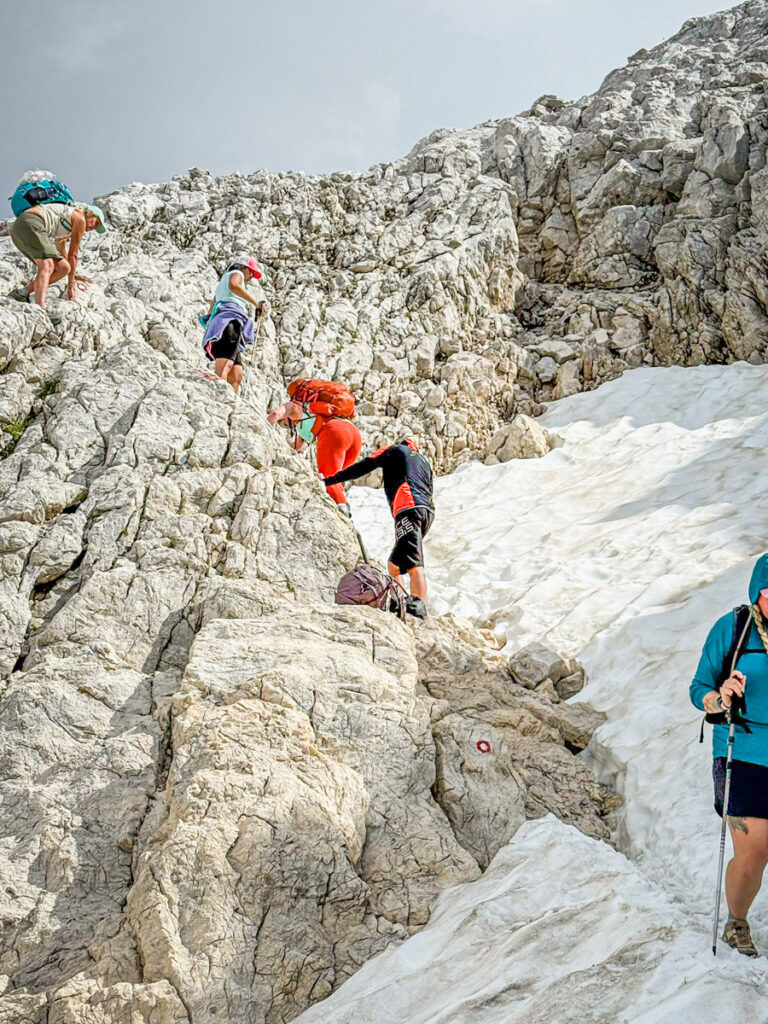 people climbing down rocks near snow mt triglav