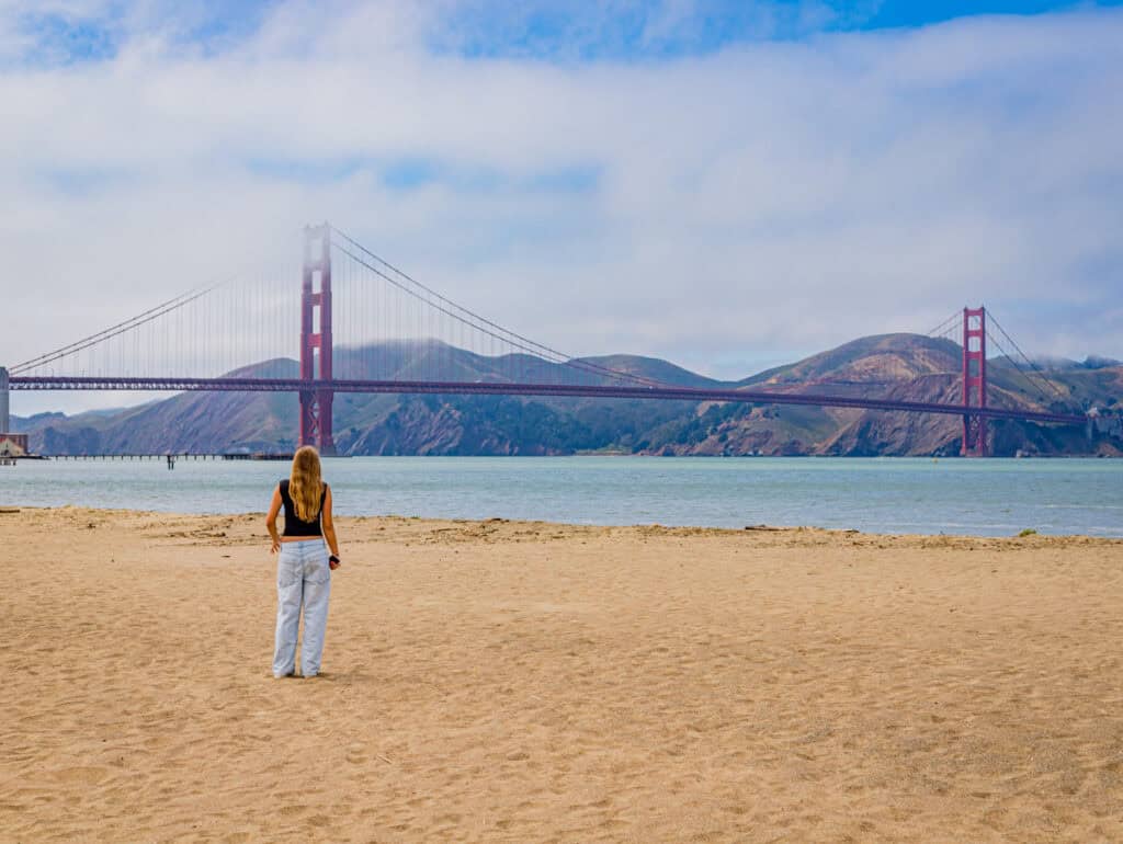 girl looking at golden gate bridge from the beach