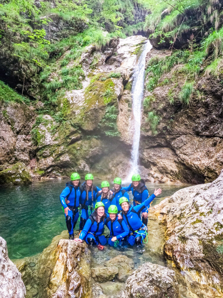 group of women standing in pool in canyon with waterfall