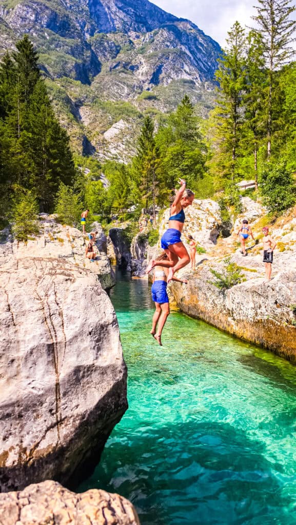 couple jumping off rock into soca river